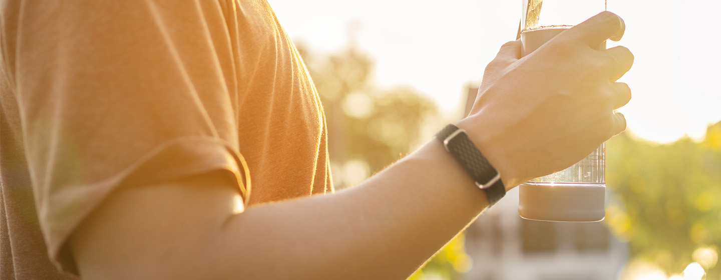 Mann hält Wasserflasche in der Hand und trägt Hilo Band um den Arm