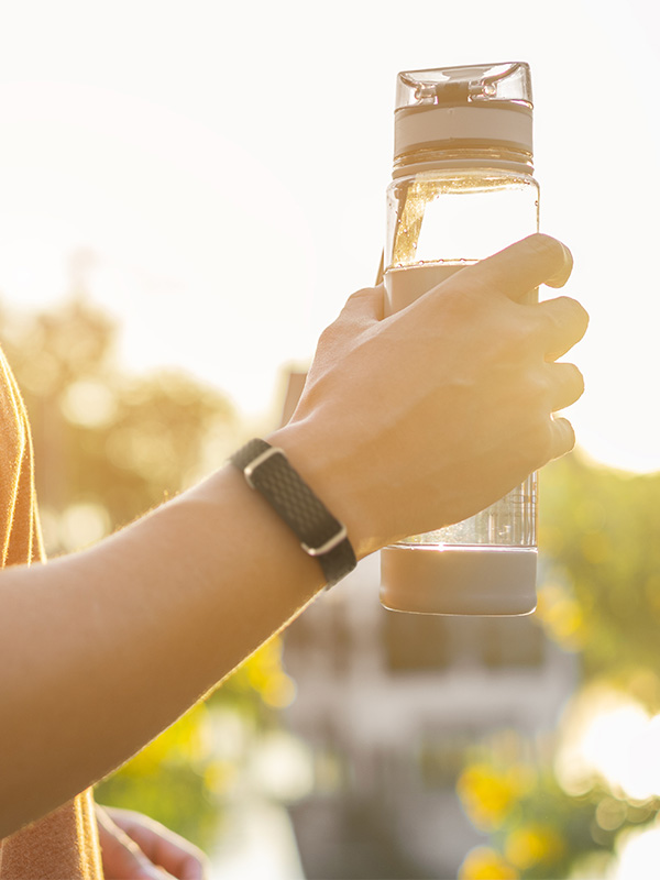 Mann hält Wasserflasche in der Hand und trägt Hilo Band um den Arm
